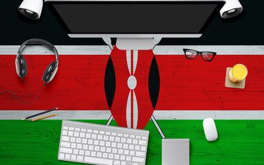 Kenya flag background with headphone,computer keyboard and mouse on national office desk table.Top...