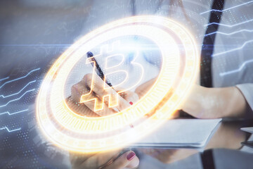 Cryptocurrency hologram over woman's hands writing background. Concept of blockchain. Double...