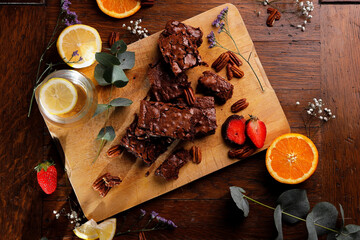 Delicious Brownies on a rustic wooden table with strawberries, oranges and lemons