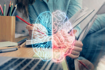 Double exposure of woman's writing hand on background with brain hud. Concept of learning.