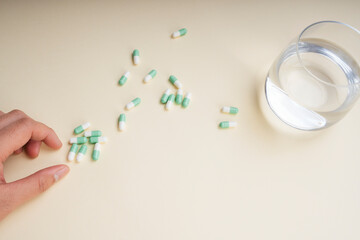 Top view - Hand of human taking drug medicine pills with glass of water.