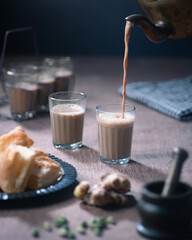 Indian Masala Cutting Chai being poured into a glass. Served with Khari Biscuits