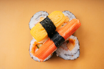 Top view - Egg roll crab stick sushi on sushi roll over yellow background.