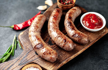 grilled sausages with spices and rosemary on a stone background