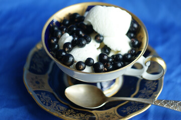 blackcurrant and ice cream. blackcurrant berries on a white vanilla ice cream in a vintage cup