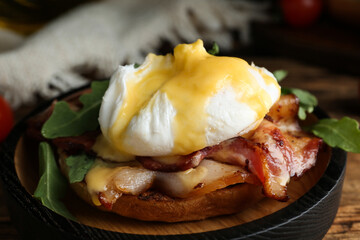 Delicious egg Benedict served on wooden table, closeup