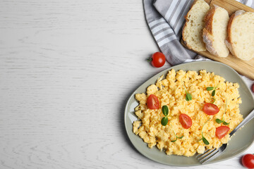 Tasty scrambled eggs served on white wooden table, flat lay. Space for text