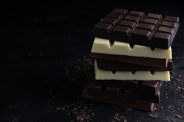 Different tasty chocolate bars on black table. Space for text