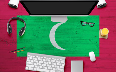 Maldives flag background with headphone,computer keyboard and mouse on national office desk table.Top view with copy space.Flat Lay.