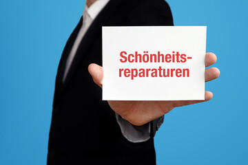 Schönheitsreparaturen. Geschäftsmann im Anzug hält Karte in die Kamera. Der Begriff Schönheitsreparaturen steht im Schild. Symbol für Business, Finanzen, Statistik, Analyse, Wirtschaft
