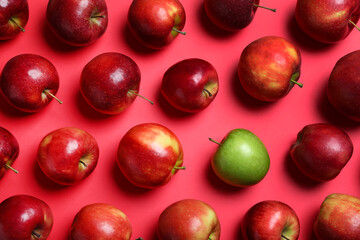 Green apple among red ones on color background, flat lay