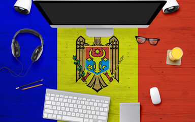 Moldova flag background with headphone,computer keyboard and mouse on national office desk table.Top view with copy space.Flat Lay.
