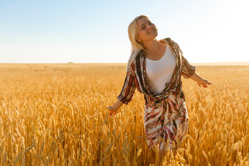 A girl in the midst of wheat spikelets. Caucasian woman posing with spikelets outside.