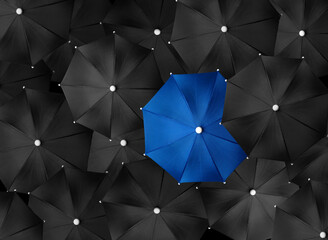 Concept image with lots of black umbrellas and a blue umbrella that stands out, be unique