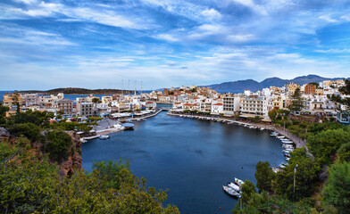 Fototapeta na wymiar Colorful view of Voulismeni lake and Agios Nikolaos town on Crete island, Greece in evening with beautiful clouds on blue sky.