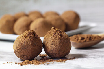 Homemade energy balls with dried apricots, raisins, dates, prunes, walnuts and cacao. Healthy sweet food. Energy balls in a plate with a wooden spoon on a marble grey background. Close up. Side view.