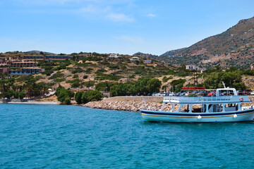 Typical view of small harbor on Greek island, hills, houses, ferry on clear sunny day, Crete, Greece