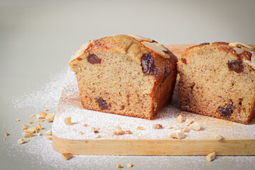 Banana cake dessert or banana bread placed on a wooden plate, with almonds and sprinkled with flour, decorated to look beautiful as a portion of delicious food.