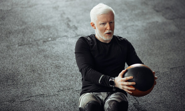 Senior Man Exercising At Gym. Mature  Man Exercising With Medicine Ball.