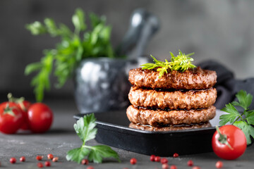 Grilled burger patties with herbs, spices on a dark background