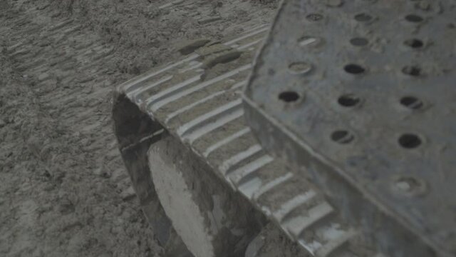 Soil compactors grading land level by running around the land.Real Close up View of a bull dozers tracks as it rolls back over the gravel it ising