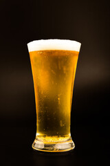Beer glass with beer bubbles on a black background.