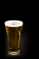 Beer glass with beer bubbles on a black background.