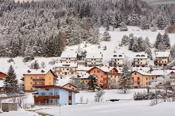 View of a small beautiful village in winter. Against background of dense forest