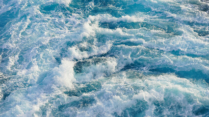 seething water. texture of blue foamy sea water. clear ocean water background. sun reflection