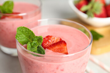 Tasty strawberry smoothie with mint in glass on table, closeup