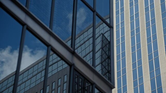 Downtown urban metropolitan closeup of tall blue and grey office buildings reflecting cinematic clouds in summer timelapse