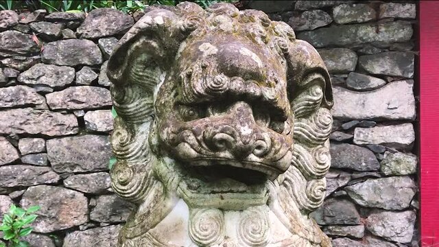 A Grungy Chinese Guardian Lion Foo Dog Sculpture At The Park - close up