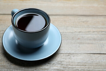 Cup of aromatic black tea on wooden table, space for text