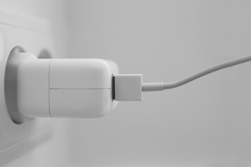 Charging adapter plugged in electric socket, closeup