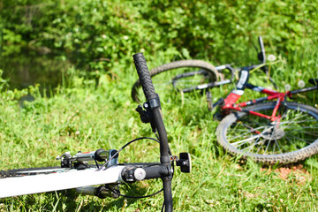 Fototapeta na wymiar two bicycles lie on green grass in the summer park