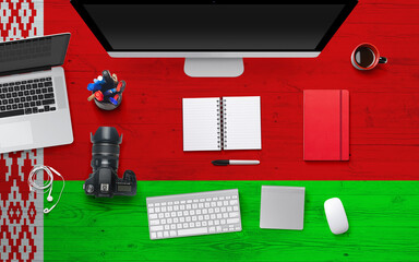 Fototapeta na wymiar Belarus flag background with headphone,camera, notebook and mouse on national office desk table.Top view with copy space.Flat Lay.