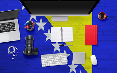 Bosnia Herzegovina flag background with headphone,camera, notebook and mouse on national office...