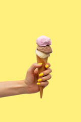 Woman's hand holding an ice cream in a yellow background