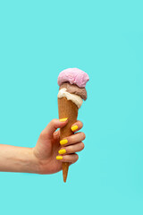 Woman's hand holding an ice cream over a light blue background