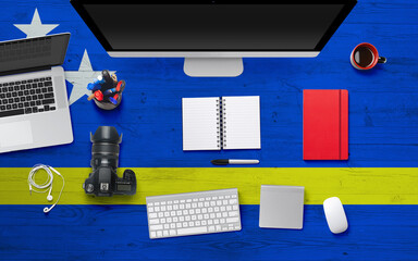 Curacao flag background with headphone,camera, notebook and mouse on national office desk table.Top view with copy space.Flat Lay.