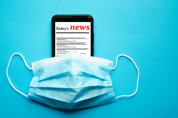 Blue medical mask on a black smartphone. Protection, disinfection of the smartphone. The mask is...