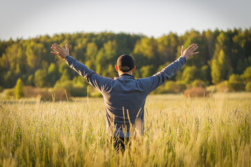 Happy man waving his hands in the field. The field background is blurred.