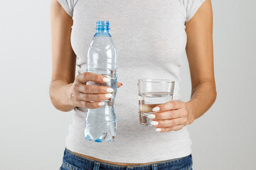 Woman holding a bottle and a glass of water in her hands.