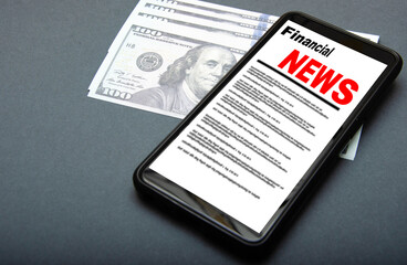 The smartphone on the screen the inscription financial news lies on dollars. 100 dollars banknotes and smartphone with financial news.