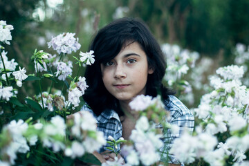 Naklejka premium A teenage girl in the garden among flowers.