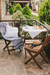 Naklejka premium Breakfast with fresh tea, fruits and cookies outdoors on a cozy terrace of country house or cottage with garden view.
