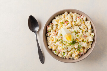 A light egg salad with celery, gherkin, pepper and mayonnaise. Served in a bowl on a light background. Top view.