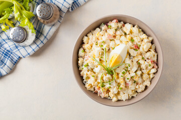 A light egg salad with celery, gherkin, pepper and mayonnaise. Served in a bowl on a light background. Top view.