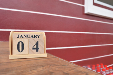 January 4, Number cube with wooden table beside the wall.
