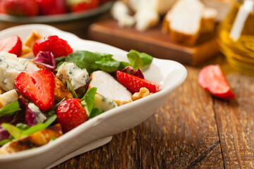 Delicious salad with fried chicken, blue cheese, strawberries and walnuts. Front view.